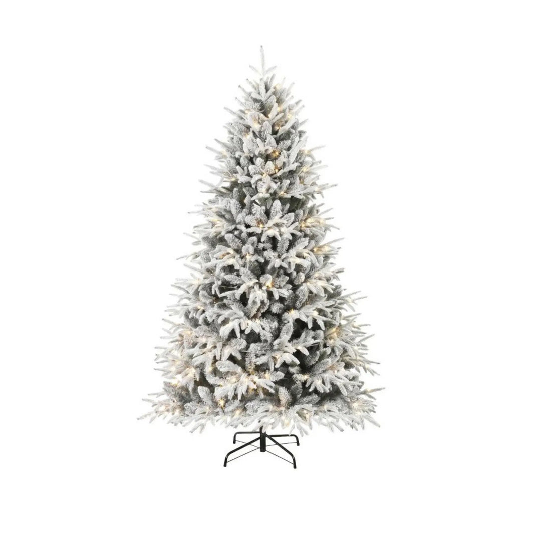 Fyllig snöflockad julgran med ljus