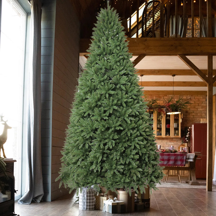 Stor upplyst julgran med varmvita och färgade lampor