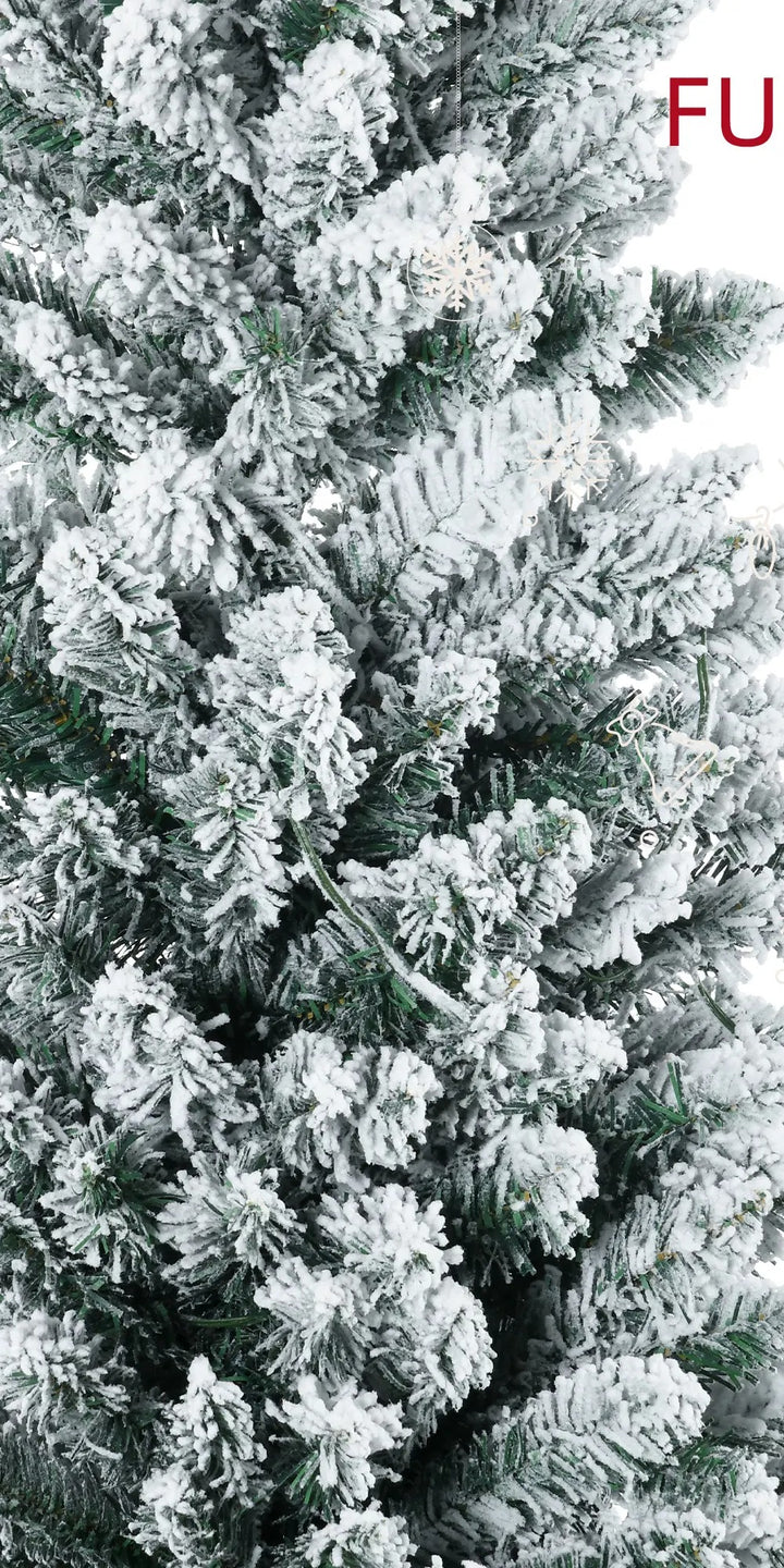 Snöig smal julgran med varma ljus