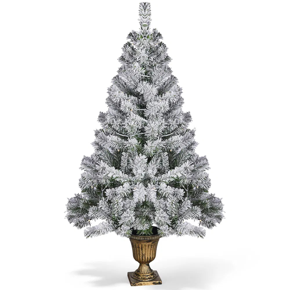 Snöflockad julgran i kruka med ljus