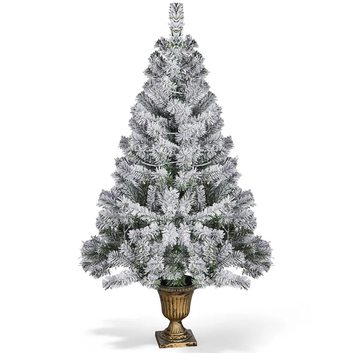 Snöflockad julgran i kruka med ljus
